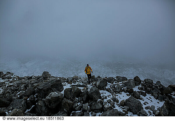 A man treks from Everest Base Camp in a dark storm.