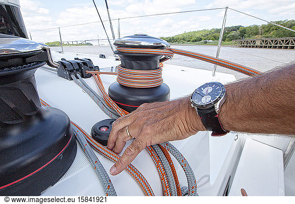 A man using the winch system on a luxurious catamaran cruising on the Garonne river