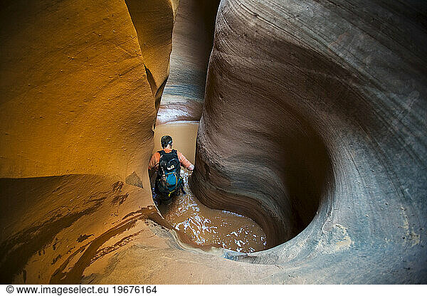 A man wading in water in sculpted slot canyon  Utah.