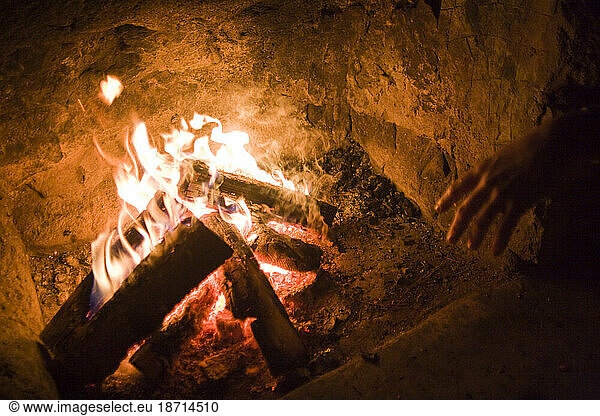 A man warms his hands by an evening fire at the Bluebell shelter in Chautauqua Park  Boulder  Colorado.
