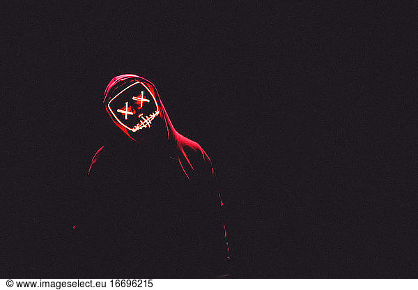 A Man Wearing A Red Hoodie With Red Glowing Mask In The Dark Backgroun