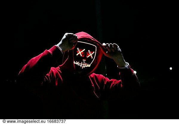 A Man Wearing A Red Hoodie With Red Glowing Mask In The Dark Backgroun