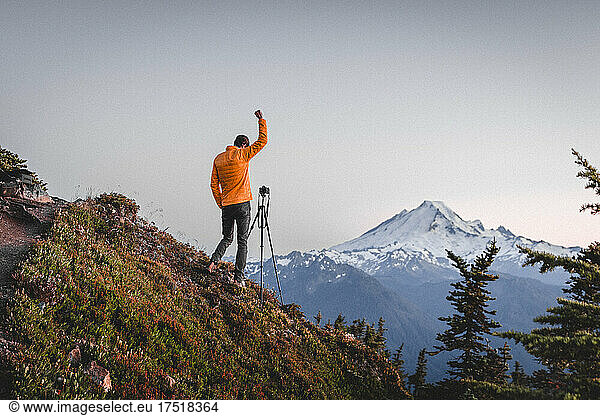 A man with a camera is taking pictures of mt. Baker