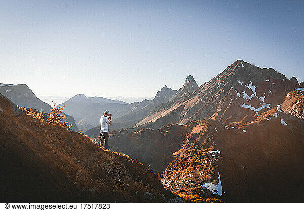 A man with a cameras taking pictures of mountains in North Cascades