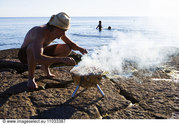 A man with an outdoor grill on the beach.
