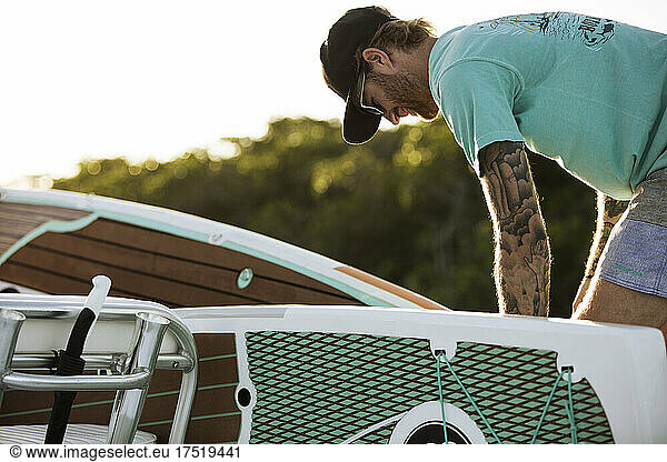 A man with tattoos loads up paddle boards on boat