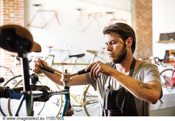 A man working in a bicycle repair shop  checking the frame of the bike.