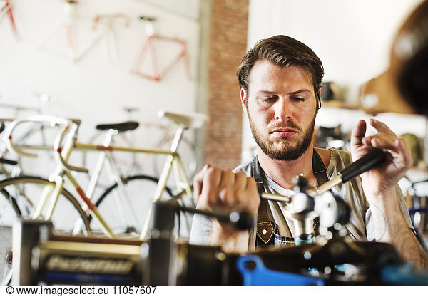 A man working in a bicycle repair shop  checking the frame of the bike.