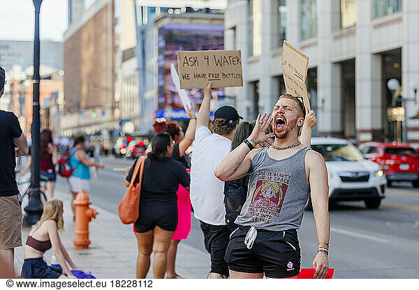 A man yelling loudly at a protest along city street