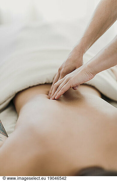 A massage therapist works on a female patient's back