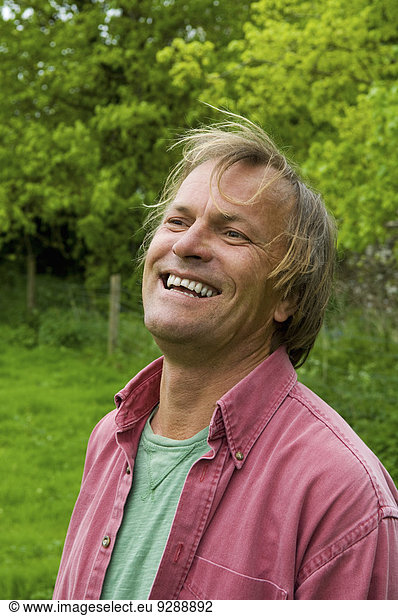 A mature man in casual clothes with blonde hair  smiling broadly.