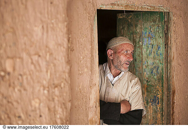 A mature man in traditional clothing stands in a doorway looking out in Ait Benhaddou  Morocco  a small village in the High Atlas Mountains where such films as Lawrence of Arabia and Gladiator were filmed; Ait Benhaddou  Morocco