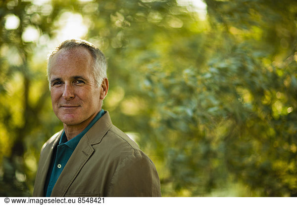 A mature man wearing a green shirt  in woodland.
