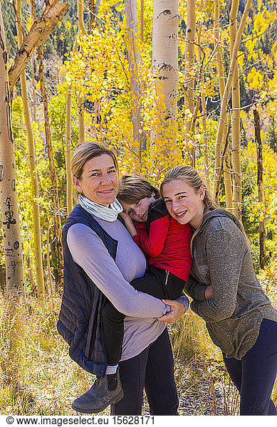 A mature woman  boy and girl  a mother and her two children in woodland  aspen trees in autumn colour