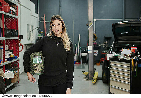 A mechanic woman looking at the camera in a garage