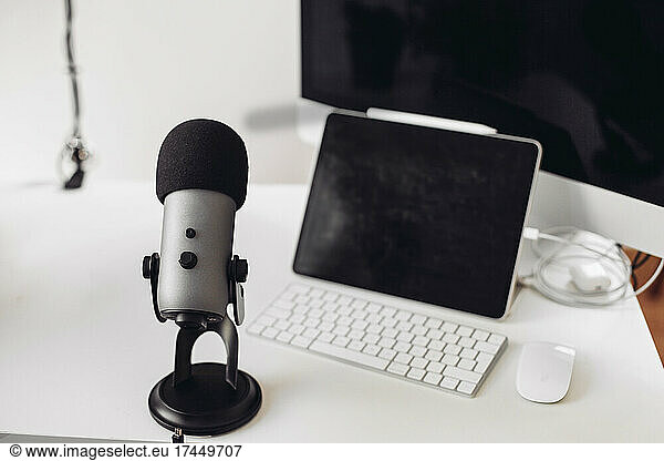A microphone  tablet  computer  white mouse  wires on a white table