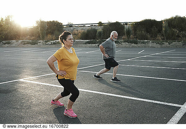 A middle-aged couple are exercising in a car park