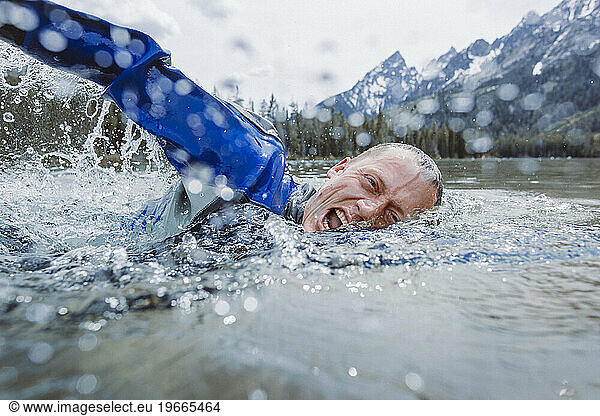 A middle aged male diver surfaces to take a breath.