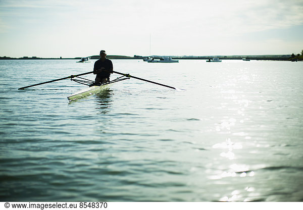 A middle-aged man in a rowing boat on the water.