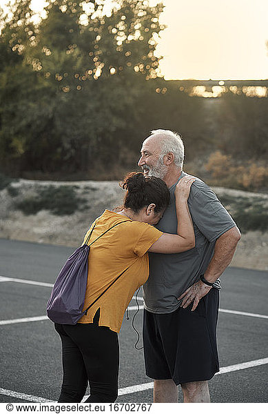 a middle-aged woman leans on her husband's chest for sport