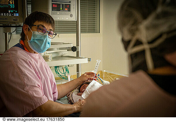 A midwife and a mother take care of a premature baby.