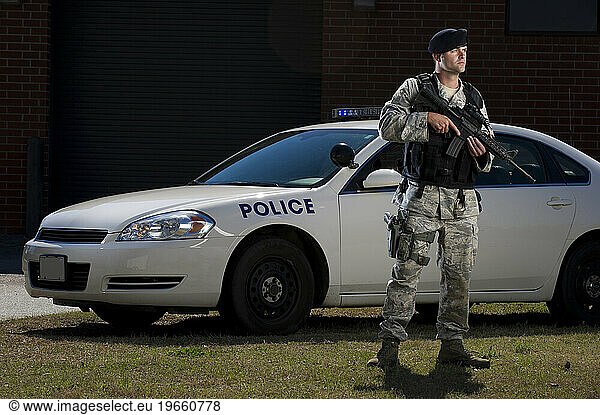 A military police officer makes a call over the radio near his police cruiser.