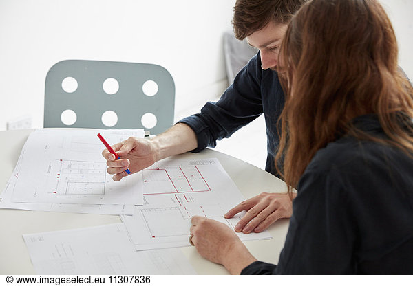A modern office. Two people at a meeting discussing plans and drawings  Architectural drawings.