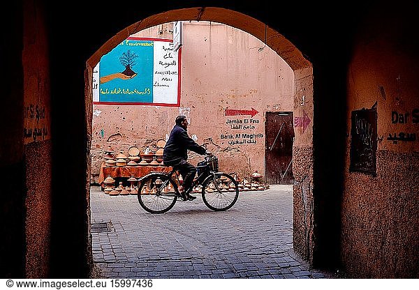 A Moroccan man cycles through the Medina in Marrakech  Morocco  North Africa.