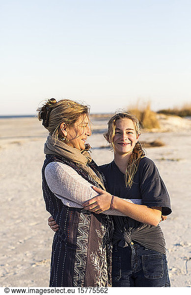 A mother and daughter embracing on a beach