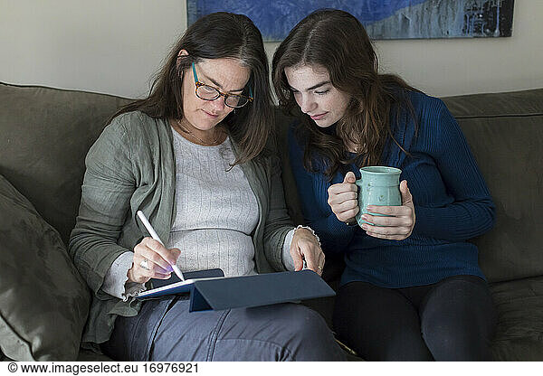 A mother and daughter work on a tablet together