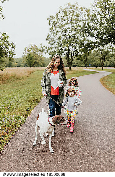 A mother and daughters walk their family dog along walking path