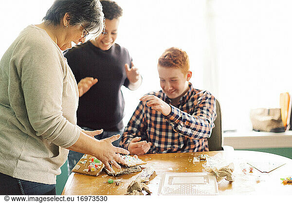 A mother and her children making a gingerbread house at dining table