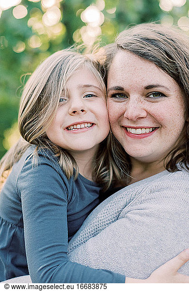 A mother and her daughter in a close hug and smiling