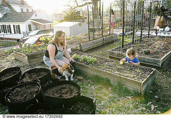 A mother and her daughters tending to their growing garden in spring
