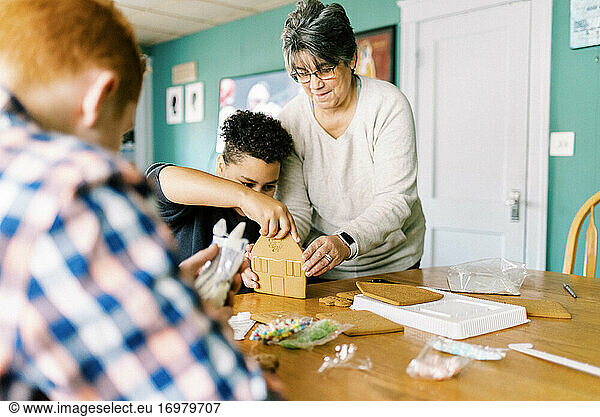 A mother and her kids making a gingerbread house for christmas