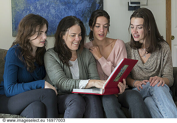 A mother and her three daughters look at a photo album together