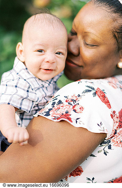 A mother lovingly holding her smiling infant