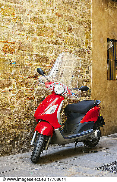 A Motor Scooter Parked Beside A Stone Wall; Barcelona  Spain