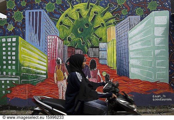 A motorcyclist passes in front of murals in Depok  West Java  which tell of a Coronavirus monster amid the city that killed tens of thousands of people during the Coronavirus (COVID-19) outbreak  April 16  2020.