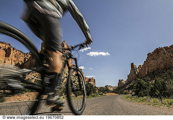 A mountain biker passes by in a blur on a road in southwest desert scenery.