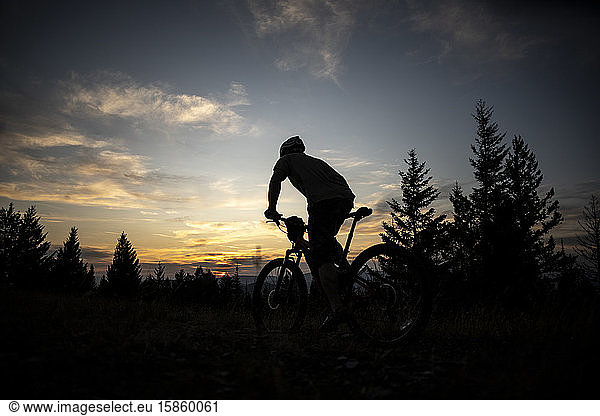 A mountain biker rides towards the sunset on top ofBlue Mountain