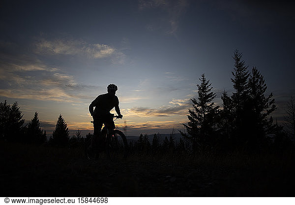 A mountain biker silhouetted at sunset on the top of Blue Mountain.