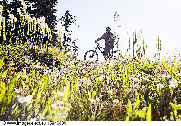 A mountain biker stands in Bear Grass and takes in the view