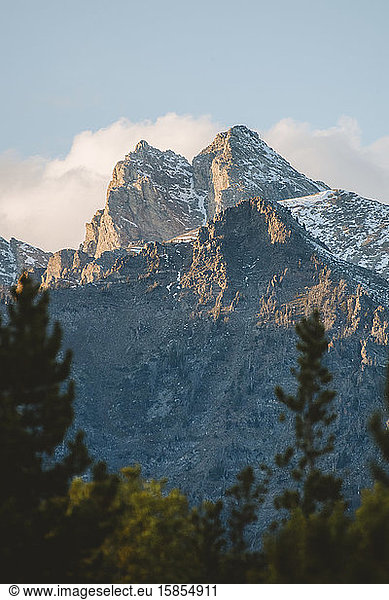 A mountain peak is illuminated by golden rays from the setting sun.