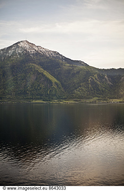 A mountain peak towering over a lake  creating a reflection on the calm water surface.