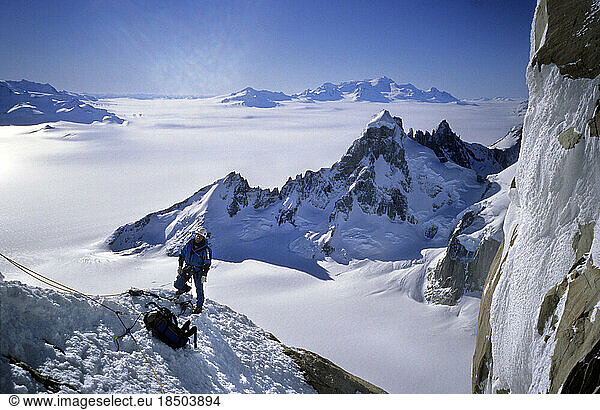 A mountaineer climbs onto a ridge on Cerro Torre's northwest face  with Cerro Rincon  Volcan Lautaro and the Continental Iceca