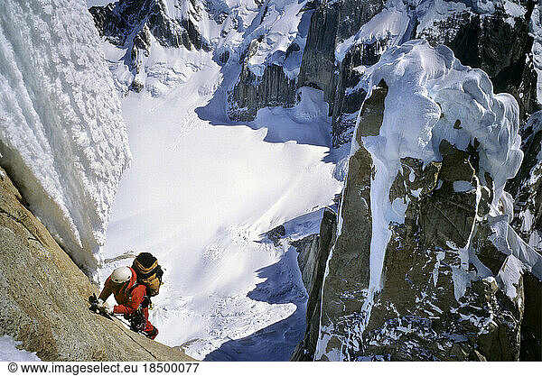 A mountaineer climbs up Cerro Torre's north face  with the ice capped summit of Torre Egger in the background  in Argentine Pata