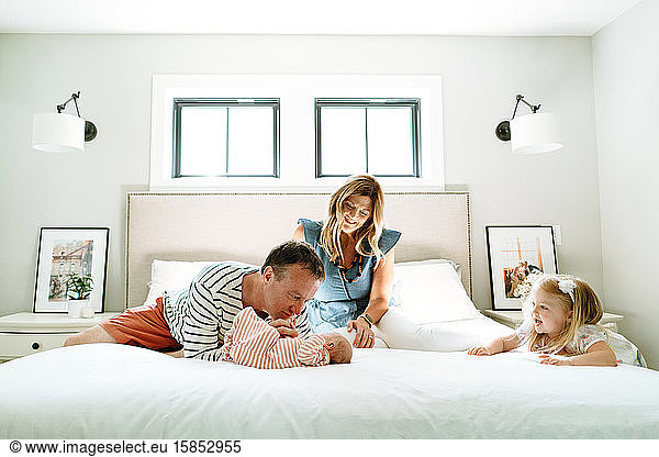 A new family of four playing together in a modern bedroom