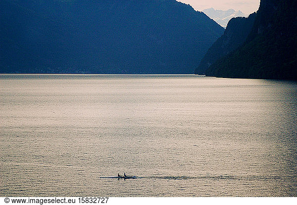 A pair of rowers glide through the calm waters of Lake Lucerne