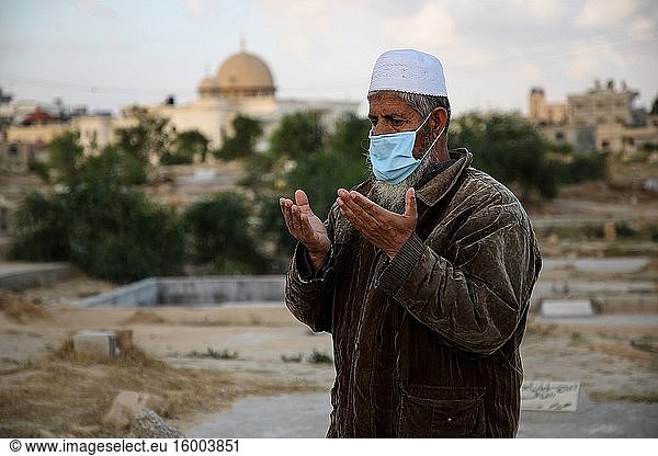 A Palestinian Muslim prays next to the grave of a relative while wearing a face mask as a precaution against COVID-19  during Eid Al-Fitr Festival. Eid Al-Fitr marks the end of the holy fasting month of Ramadan. May 24  2020.
